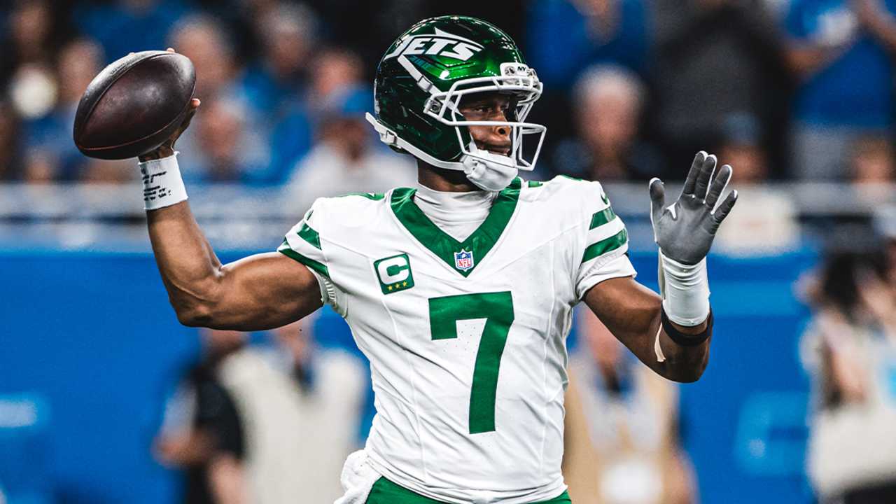 Geno Smith draws back the football to throw, wearing his white Jets number 7 jersey and green helmet.